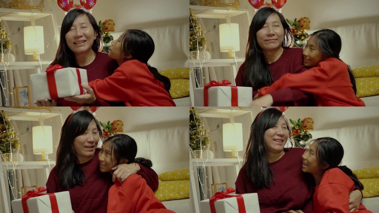 快乐的亚洲女孩给她的母亲送礼品盒与圣诞装饰品背景，生活方式的概念。