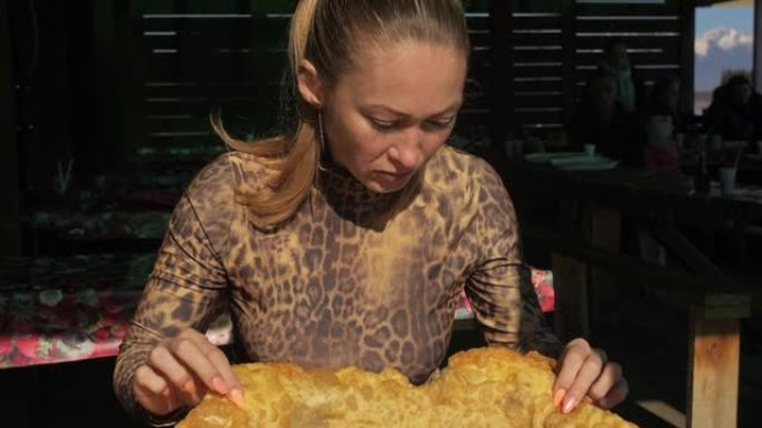 吃国家布里亚特蒙古菜cheburek的女人。大xxxl 68厘米heburek用奶酪肉洋葱煎入油锅中