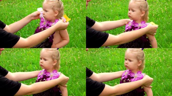 女人给可爱的小女孩穿上由花朵和叶子制成的紫色幻想连衣裙