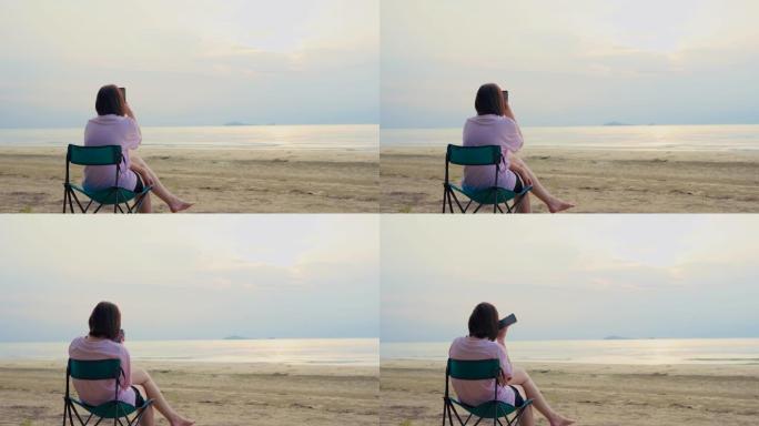 4K VDO背面独奏亚洲女人放松并在沙滩椅子上用手机拍照，夏天快乐快乐