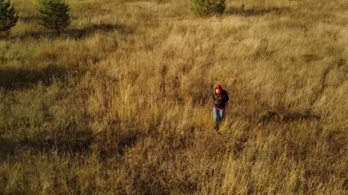秋天在荒凉的地方上孤独女人的鸟瞰图。女性独自在乡村的干草地面上行走的鸟瞰图