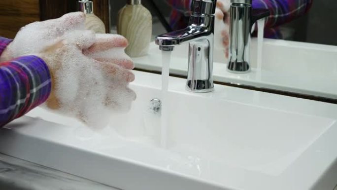 用肥皂洗手，一个人在自来水下密集洗手，身体卫生，注意双手的清洁。