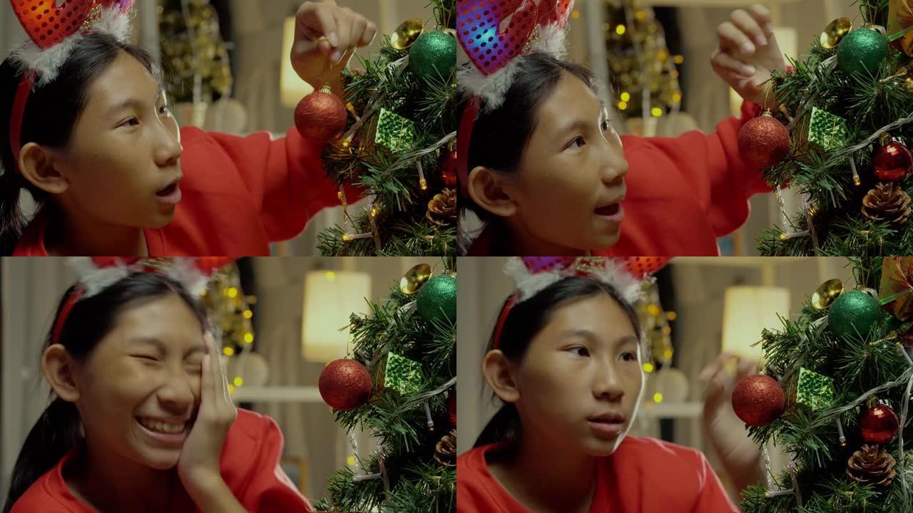 快乐的亚洲女孩穿着红色毛衣装饰圣诞树，家里有温暖的色调，生活理念。