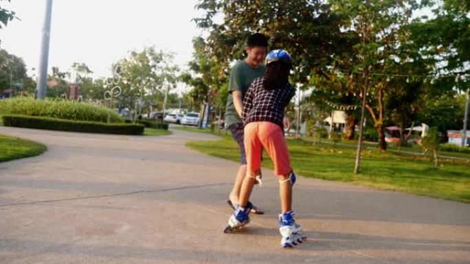 亚洲男孩教他的妹妹在公园里用太阳光玩旱冰鞋，生活方式概念。