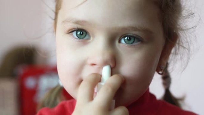 一个小女孩用喷雾剂喷到鼻子里，进行家庭治疗
