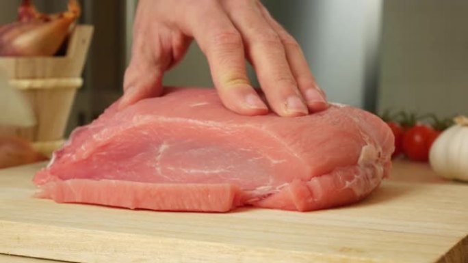 用刀切肉，在木板上切白牛肉，手拿刀。在家庭厨房烹饪