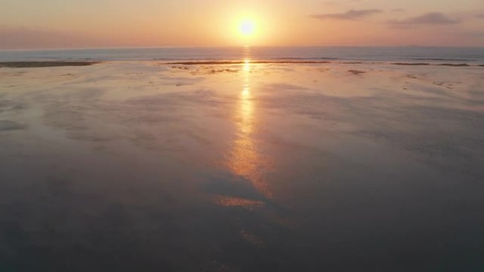 无人机在退潮海滩上朝着海上日出