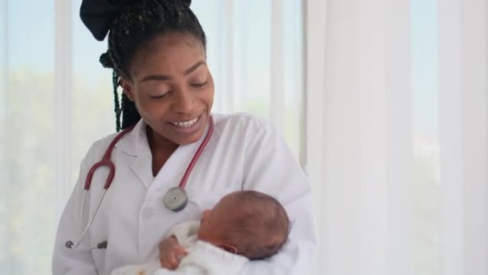 非裔美国女医生将正在睡觉的新生婴儿抱在胸前，看起来像是在白色窗帘前唱歌婴儿睡觉