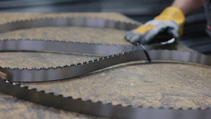 工业锯木厂的备件。刚才锯钢刀片的齿来自焊接工业锯木厂刀片的机器。工人把锯片收集在一起。特写