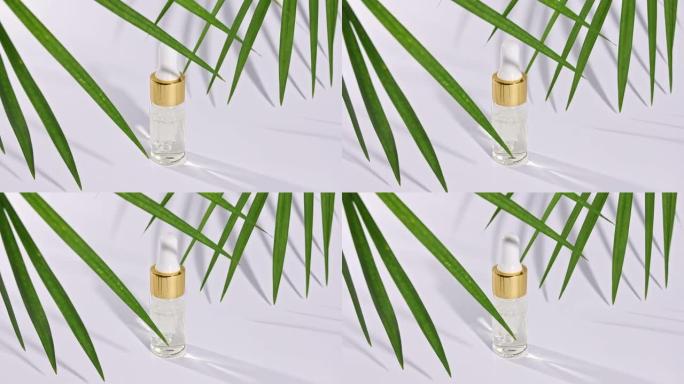 滴管玻璃瓶，天然化妆品，精油。白色背景上带有阴影的热带棕榈叶的运动