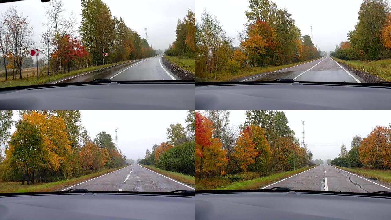 穿过雨水淋淋的前窗车，风景如画。转弯。路标转弯。挡风玻璃刮水器的运动。驾驶员观点