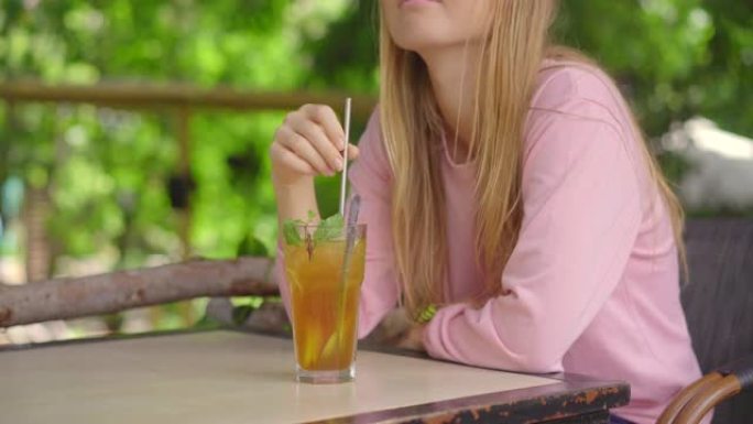 在一家环保咖啡馆中，一名年轻女子使用可重复使用的钢制吸管喝冷茶。减少使用单一塑料的概念