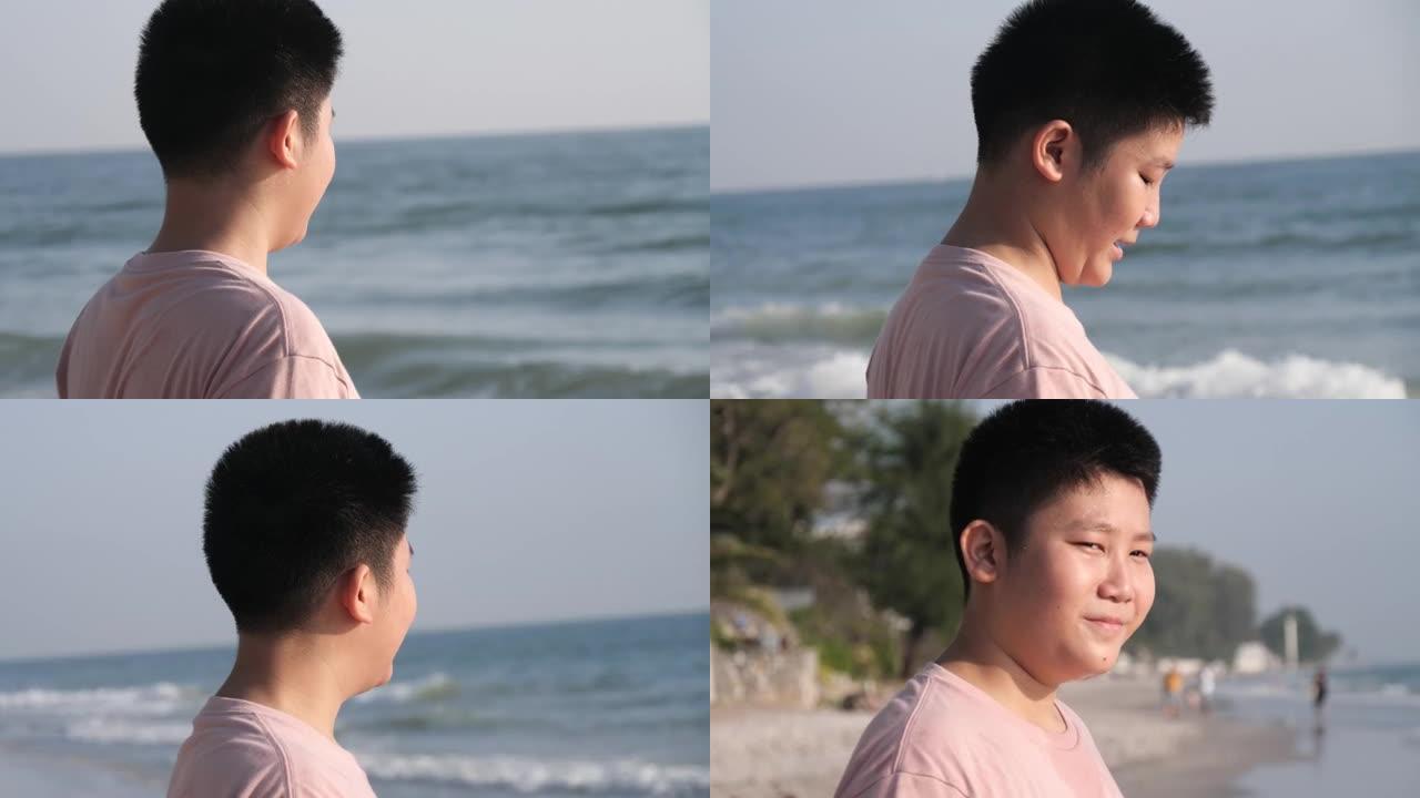 快乐的亚洲男孩早上在沙滩上享受阳光，生活方式的概念。