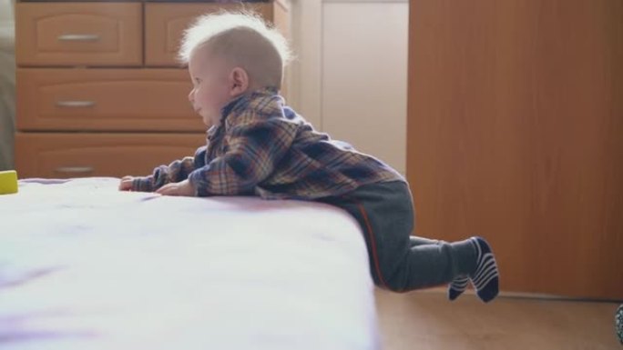 有趣的婴儿从房间地板上的大软床上下来