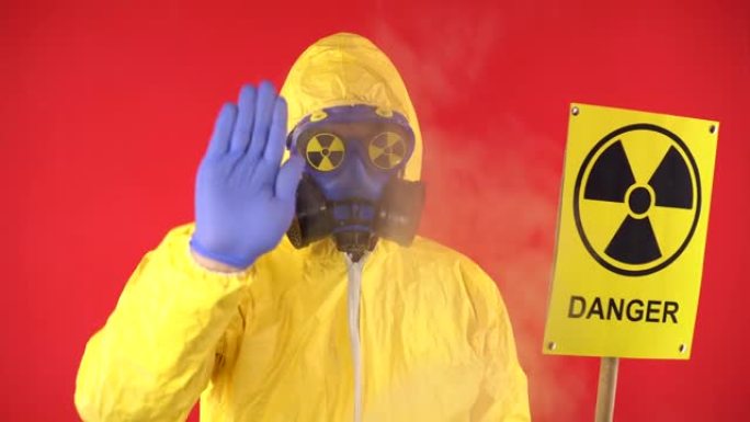 一个穿着化学黄色西装的男人的形象，戴着防护口罩和带有放射性危险迹象的眼镜。他手里拿着一张印有辐射字样