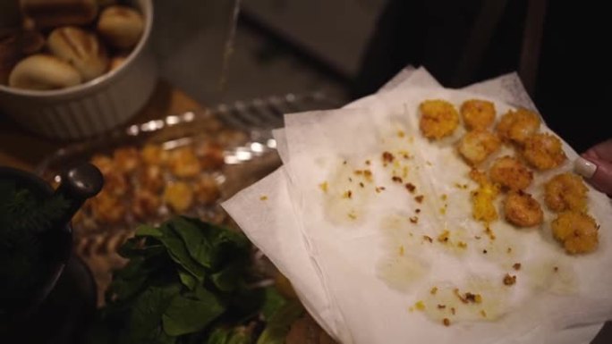 用炸虾煮熟，餐巾纸放在盘子上。光线不足。
