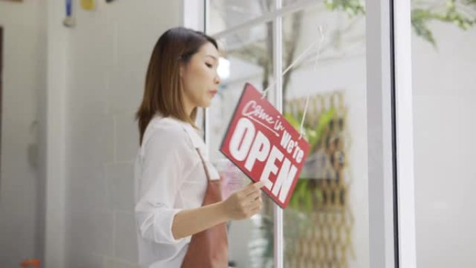 戴着口罩的亚洲女人在一家门店里从关门到开门。covid封锁后的小型食品商店业务。