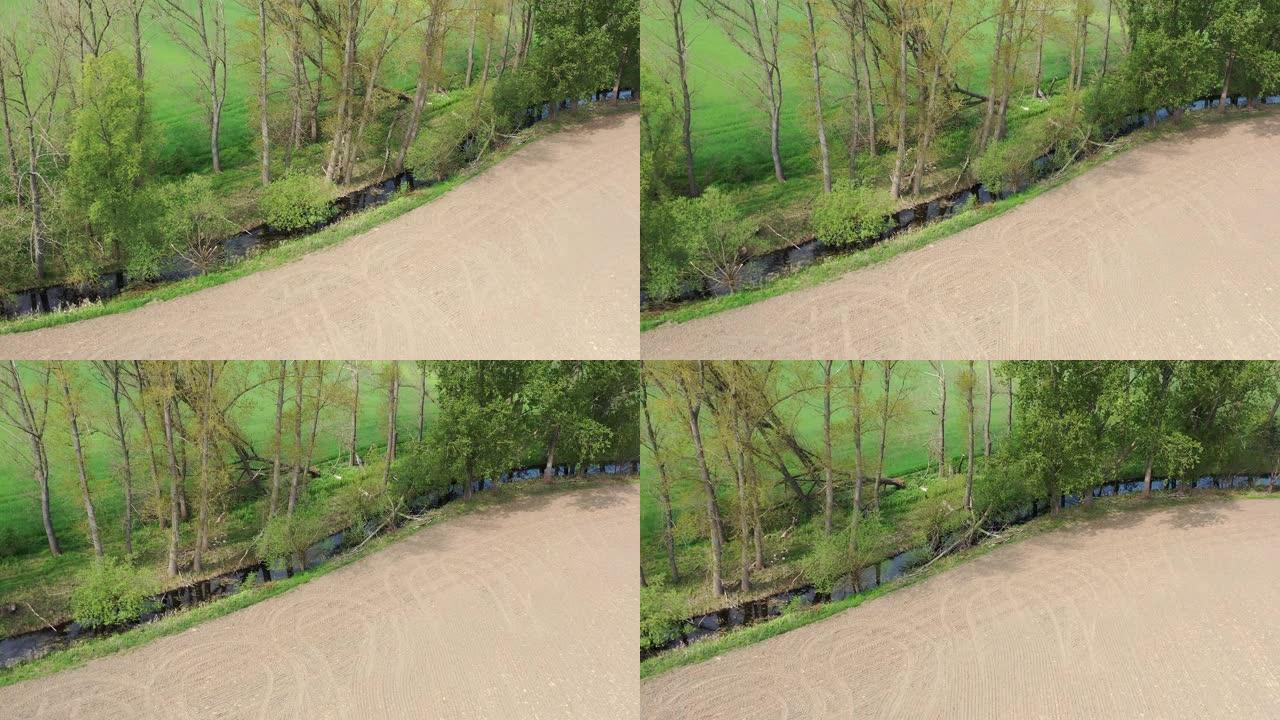 在密集使用的农田之间的河岸地带上，树木数量较高的河流的截断牛首的鸟瞰图