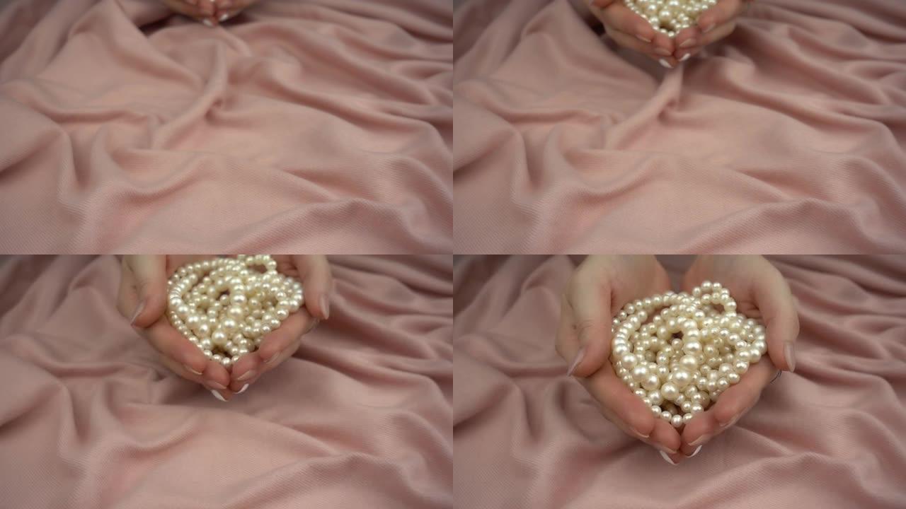 高加索女人的手握着珍珠，以慢动作展示。