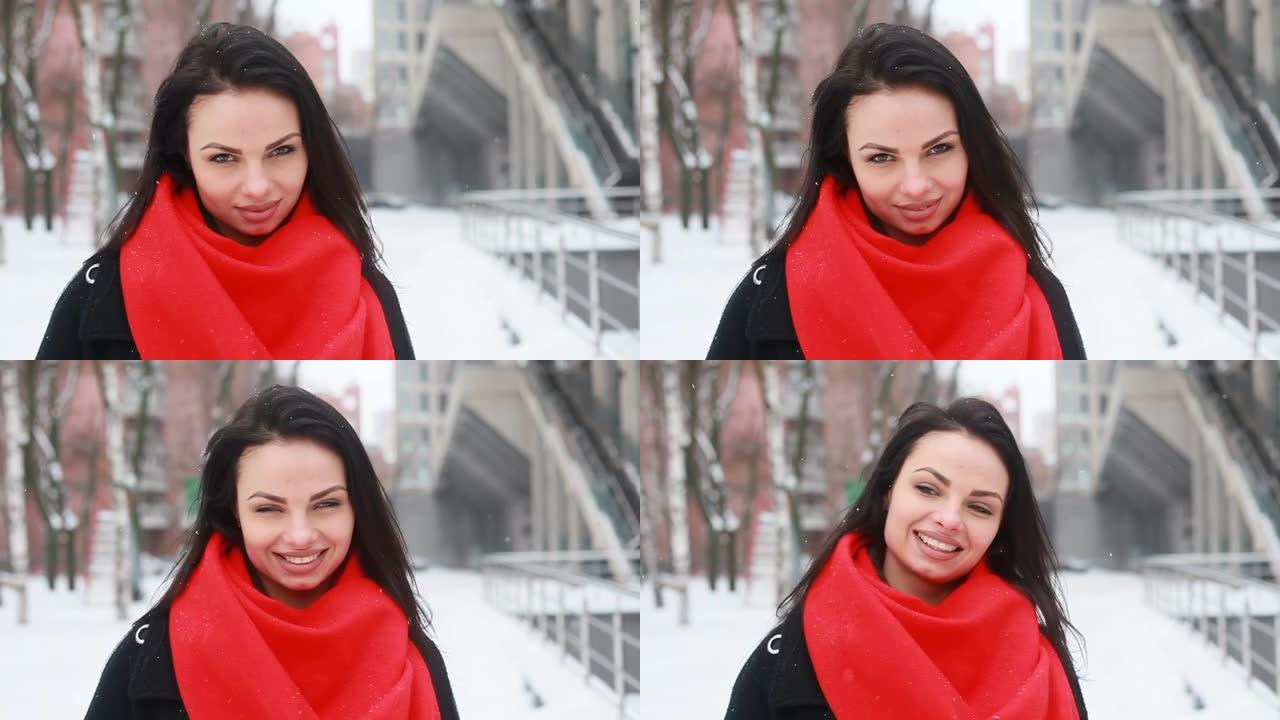 穿着黑色外套和红色围巾的年轻微笑女人在冬季城市摆姿势。