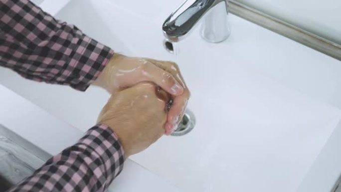 在水龙头下用水洗手，注意身体清洁，防止冠状病毒，洗掉手上的污垢，一个年轻人用肥皂彻底洗手