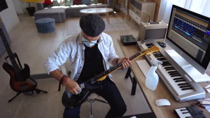 高级音乐家在他的家庭办公室工作室为吉他消毒