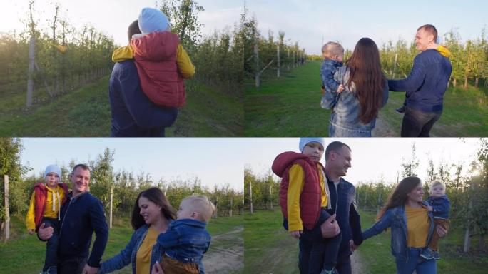 家庭关系，微笑的父母将他们的男孩抱在怀里，欢快地牵着手，在阳光和愤怒的树木的背景下沿着苹果园的道路奔