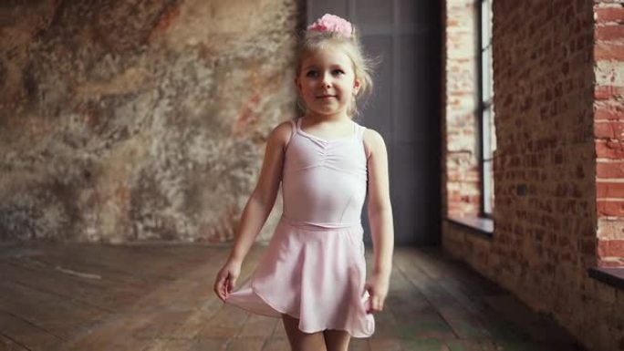 可爱的小高加索女孩金发碧眼，穿着粉色太阳裙，脚上穿着芭蕾平底鞋，微笑着