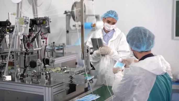 口罩工厂的工人正在使用机器在病毒爆发和粉尘污染pm2.5期间生产所需的口罩。口罩厂的工人正在检查产品