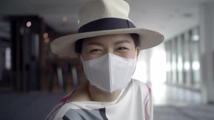 一名年轻的长发亚洲女子戴着白色帽子巡回演出，戴着带有微笑脸的防护口罩