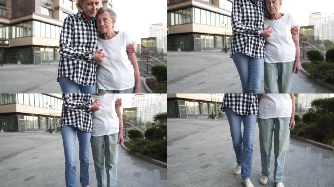 家庭价值观概念。资深女士和她患有痴呆症的年迈母亲，拥抱并微笑着在城市散步。有女儿的快乐老妇人。年老，