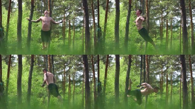 马戏团艺术家在绿色公园用空中绑带慢动作制作健美操