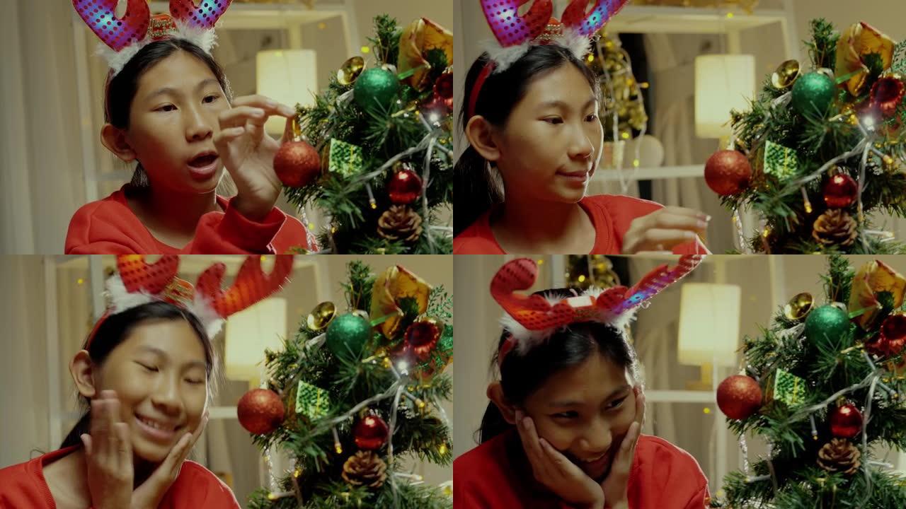 快乐的亚洲女孩穿着红色毛衣装饰圣诞树，家里有温暖的色调，生活理念。