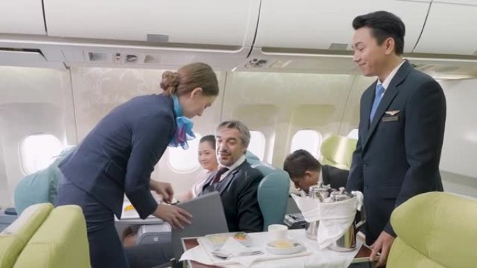 空姐在飞机上的航空公司工作人员在飞机上的客舱为商务舱的商人提供食物。