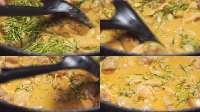有人在黑锅上搅拌沸腾的panang咖喱。泰国菜配鸡肉菜单。宏观拍摄。