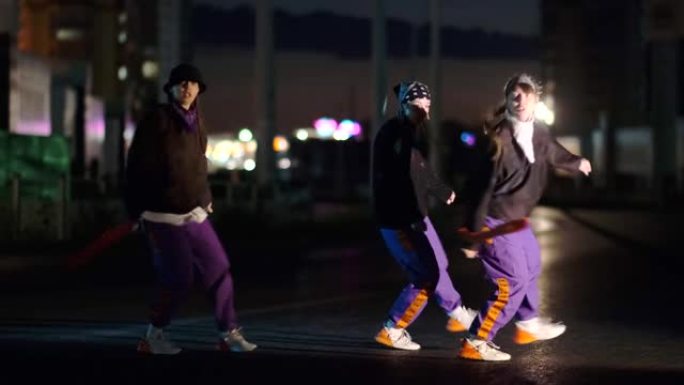 三重奏的年轻美女在夜城的街道上跳舞嘻哈，自由泳。青年生活方式和情感概念。