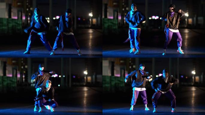 两个年轻漂亮的女人在夜城的街道上跳舞嘻哈，自由式的二重奏。青年生活方式和情感概念。