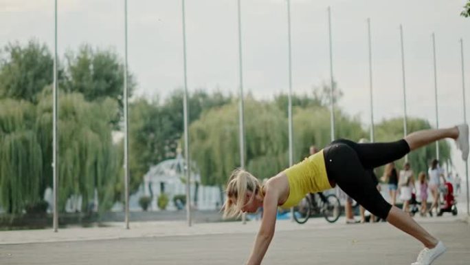 女运动员在城市的路堤上锻炼。健美女运动员在路堤上进行健身训练时斜靠地面并抬起腿的侧视图。卡尔·蔡司光
