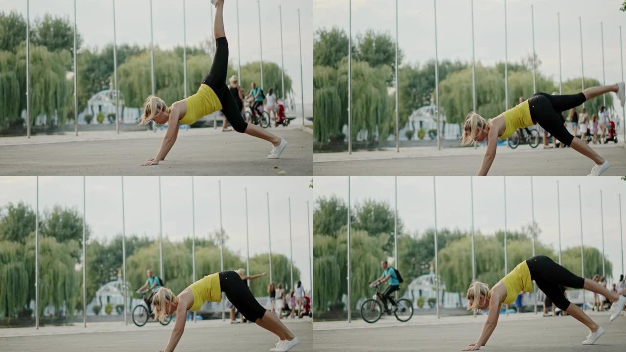 女运动员在城市的路堤上锻炼。健美女运动员在路堤上进行健身训练时斜靠地面并抬起腿的侧视图。卡尔·蔡司光