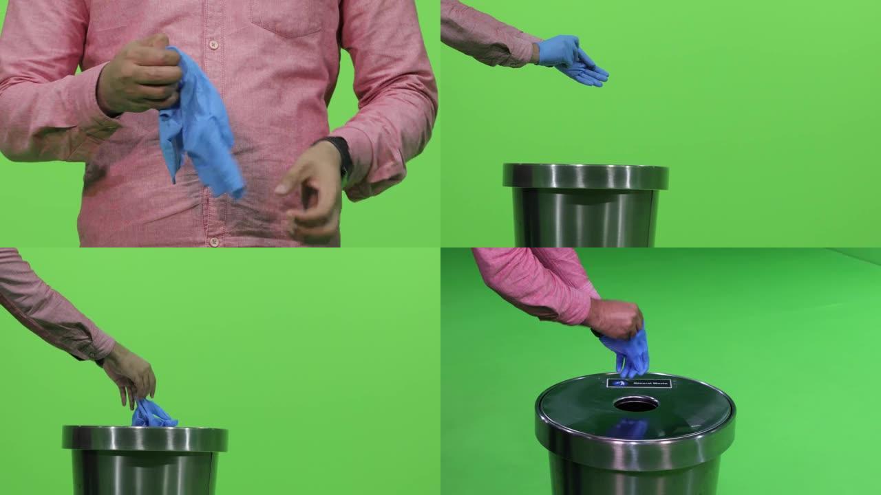 一名男性双手取下绿色背景上的蓝色医用手套，取下手套并扔进垃圾桶。