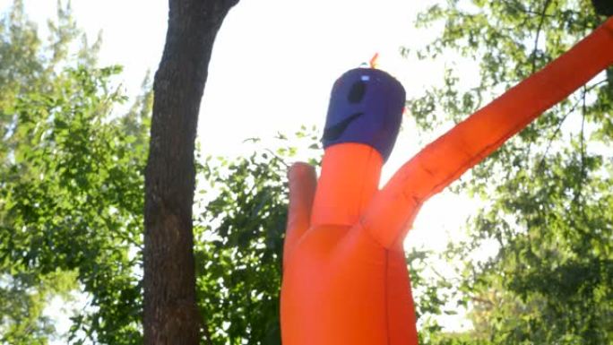 挥舞着手臂的Tube Man邀请到城市公园度过万圣节。航空通用广告标志。公园里绿树的背景上古怪的管人