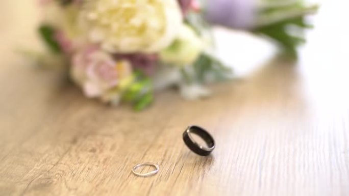 新娘花束旁边的桌子上的结婚戒指，新郎的戒指正在旋转