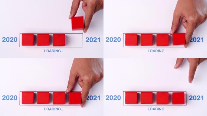 用手将木方块放入进度条中，加载快乐的新2020年2021年。新年快乐概念。