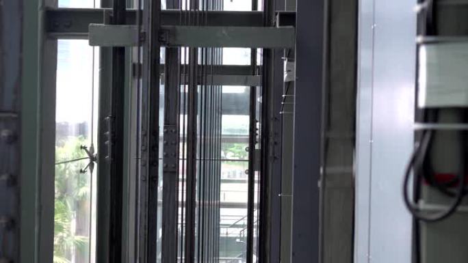 玻璃电梯正在一座现代建筑中上升。关注钢绳。