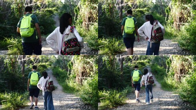 快乐的亚洲儿童带着背包在度假期间一起走在雨林中，户外冒险概念。