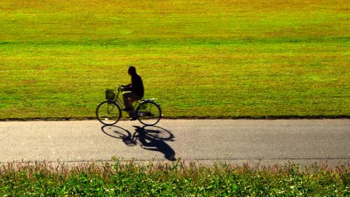 自行车经过。骑自行车的人的轮廓和阴影