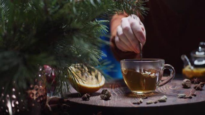 人类的手正在准备带有橙色，肉桂和豆蔻的圣诞节风味茶