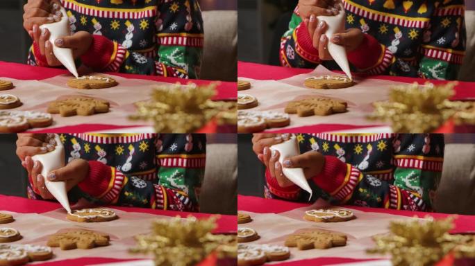穿着圣诞印花毛衣的非洲裔美国小女孩正在为传统的圣诞饼干锦上添花。在圣诞节假期装饰的厨房背景上的孩子。