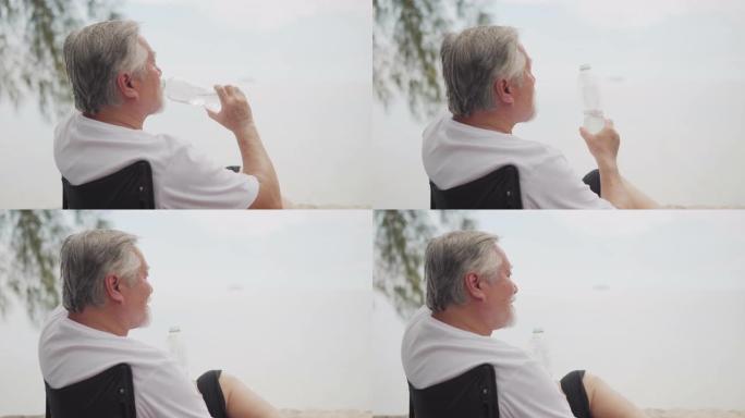 视频亚洲老人老人在沙滩上喝水。4K(UHD) 3840x2160格式。