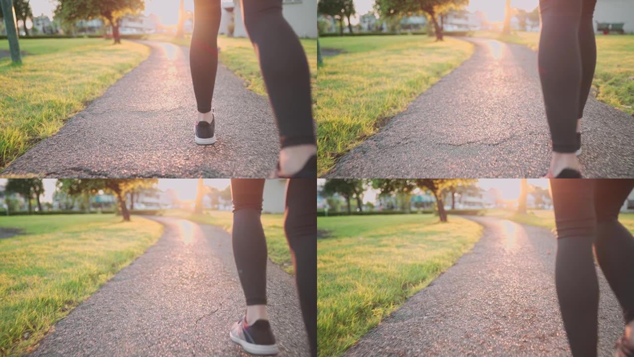 低角度射击后视年轻运动女子在公园内跑步的路径，美丽的橙色日落地平线光，有氧运动，新运动的开始分辨率正